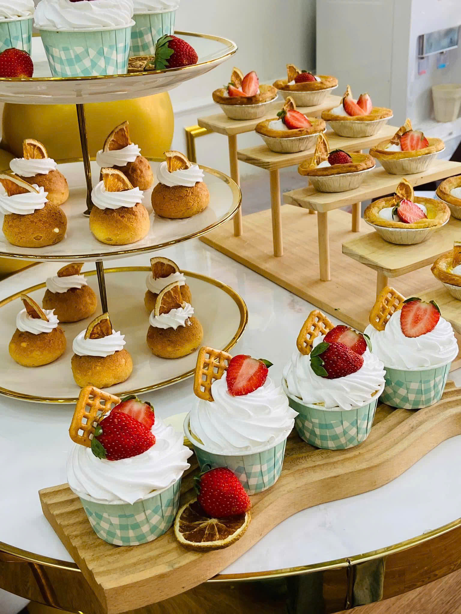 Các loại cupcake, bánh su kem và tart trái cây trên bàn tea break